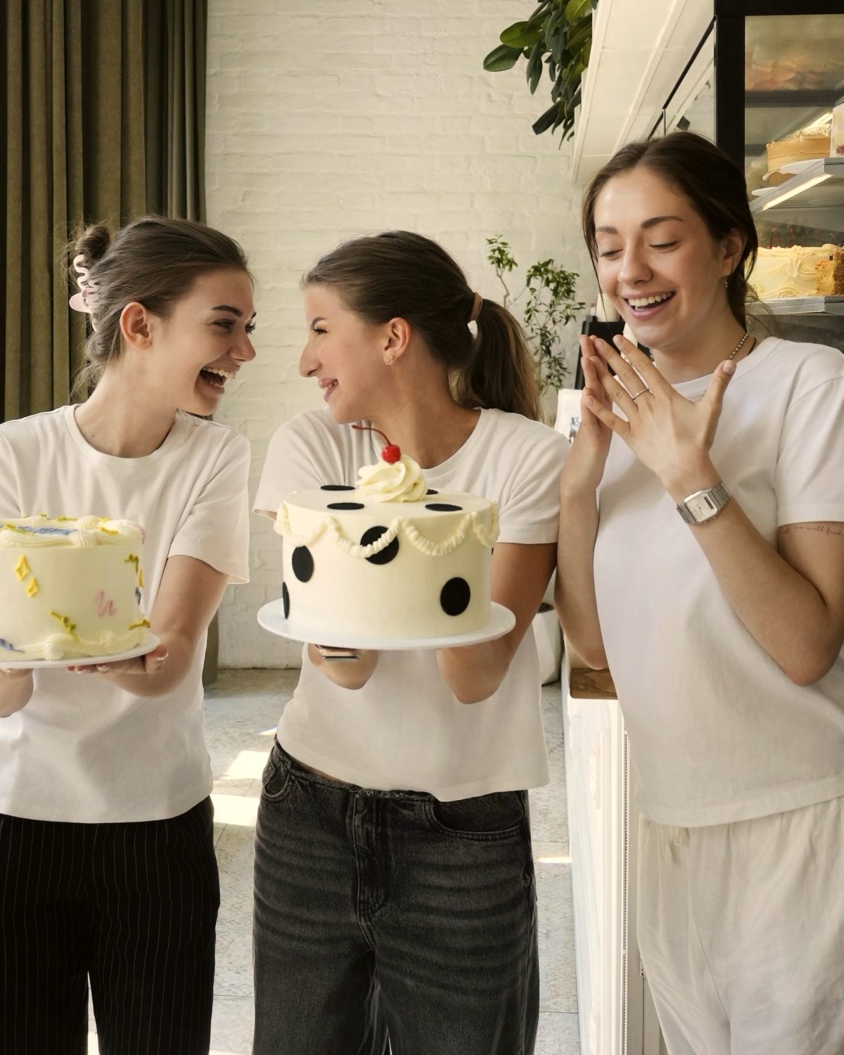 Tres personas del equipo con las tartas que acaban de decorar, en la barra